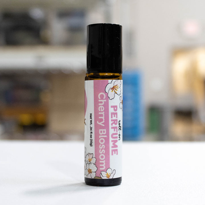A small amber glass perfume roller bottle with a black cap and a pink-and-white B&amp;F label reading &