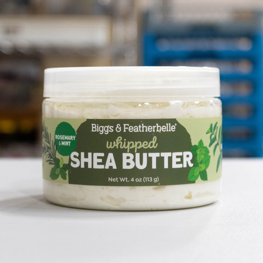 A jar of Biggs & Featherbelle whipped Shea Butter in Rosemary & Mint scent, shown on a light surface with a blurred background.