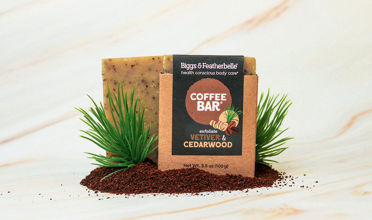 Coffee Bar by Biggs & Featherbelle branding on a wooden surface with coffee grounds and greenery.