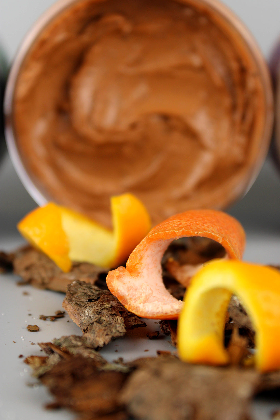 Close-up of cedar soap scrub with orange peels and cookies on a white surface